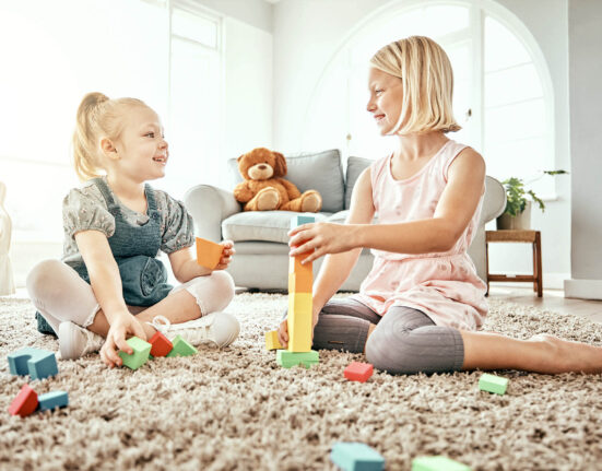 2 Mädchen spielen mit Kinder-Spielzeug, das auf dem Boden unordentlich liegt