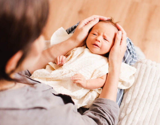 Kleines Baby traurig in Mutters Händen wegen Verstopfung oder Ähnlichem