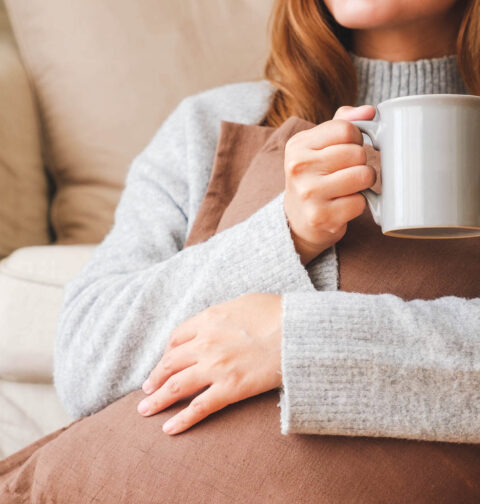 Nahaufnahme einer jungen Schwangeren, die wegen Sodbrennen heißen Tee trinkt