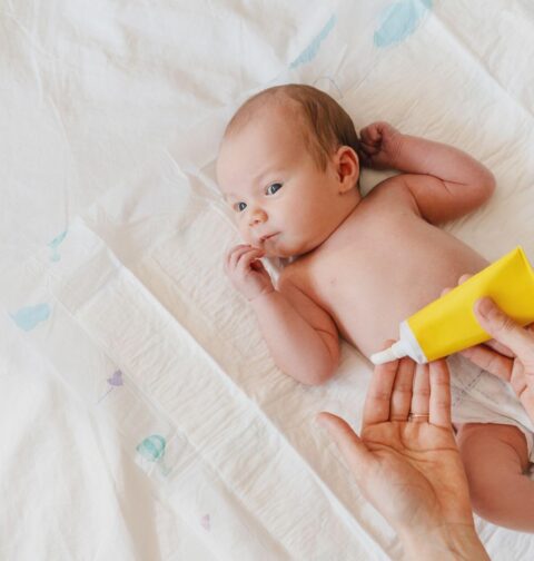 Elternteil versorgt Baby mit Creme