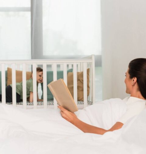 Elternteil schaut zu Beistellbett neben dem Bett