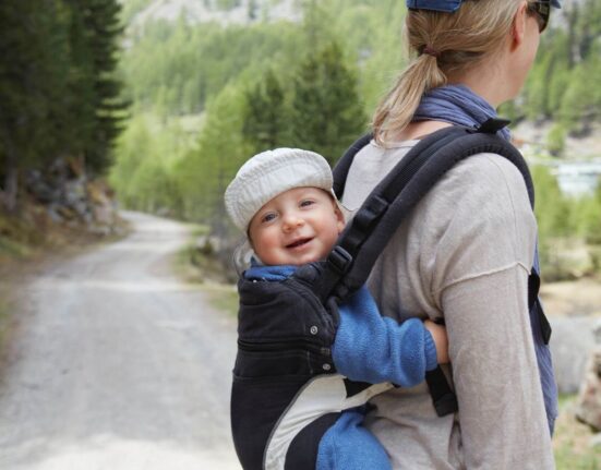 Mutter trägt Baby auf dem Rücken