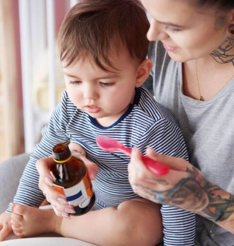 Mutter gibt Kleinkind Hustensaft