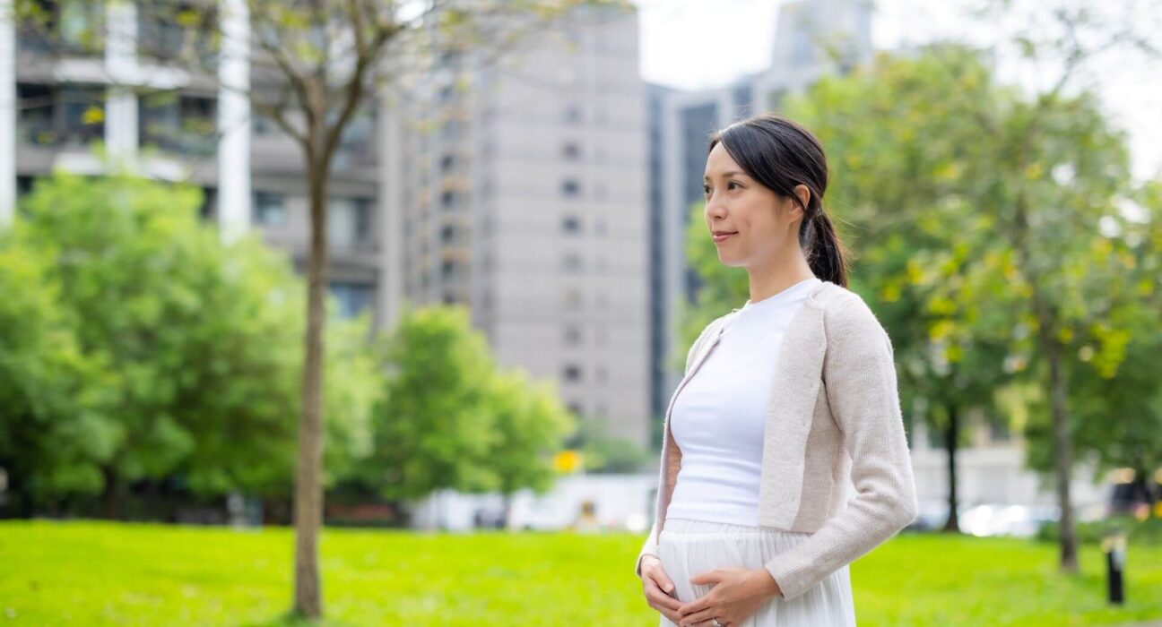 Schwangere Frau draußen hält ihren Bauch