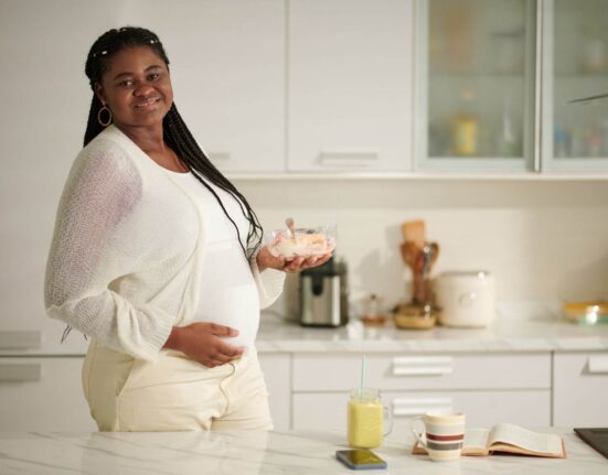 Schwangere Frau mit Essen in der Küche
