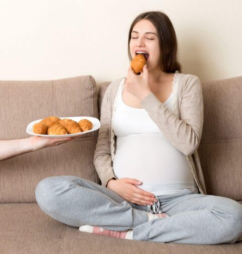 Schwangere Frau isst Croissants