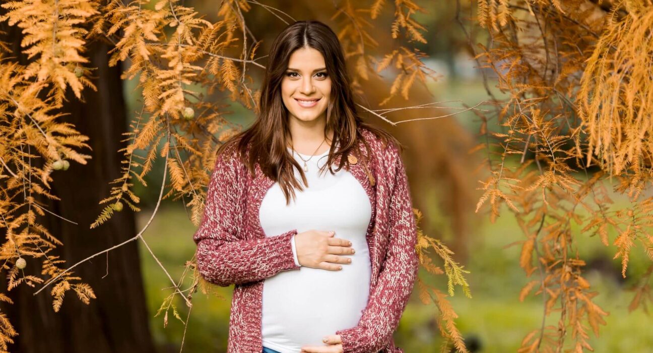 Schwangere Frau draußen im Herbst
