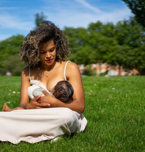 Mutter stillt ihr Baby auf einer Wiese